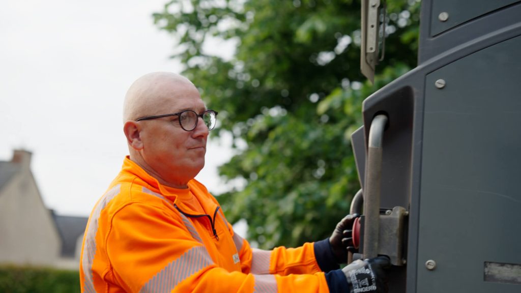 Un éboueur à l'arrière du camion poubelle pour la vidéo promotionnelle du SMICTOM Centre Ouest réalisée par Adrien Carré de 908 Films.