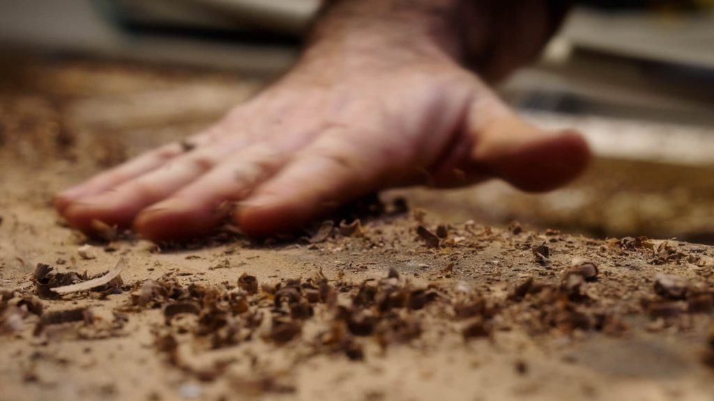 Une main essuie les copeaux de bois d'une future table créée pour le film promotionnel de Stanwood réalisé par Adrien Carré de 908 Films.