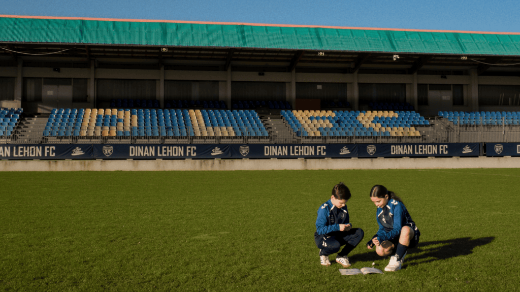 Deux jeunes joueurs du club du Dinan Léhon FC collent l'étiquette de l'Album du Club sur l'album du Dinan Léhon FC